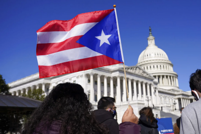 A woman waves the flag of Puerto Rico during a news conference on Puerto Rican statehood on Capitol Hill in Washington, Tuesday, March 2, 2021.